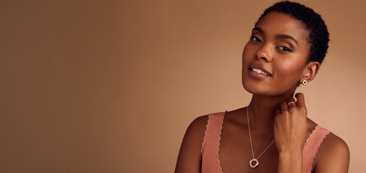 Model wearing a personalised Russian ring necklace, gold earrings and ring