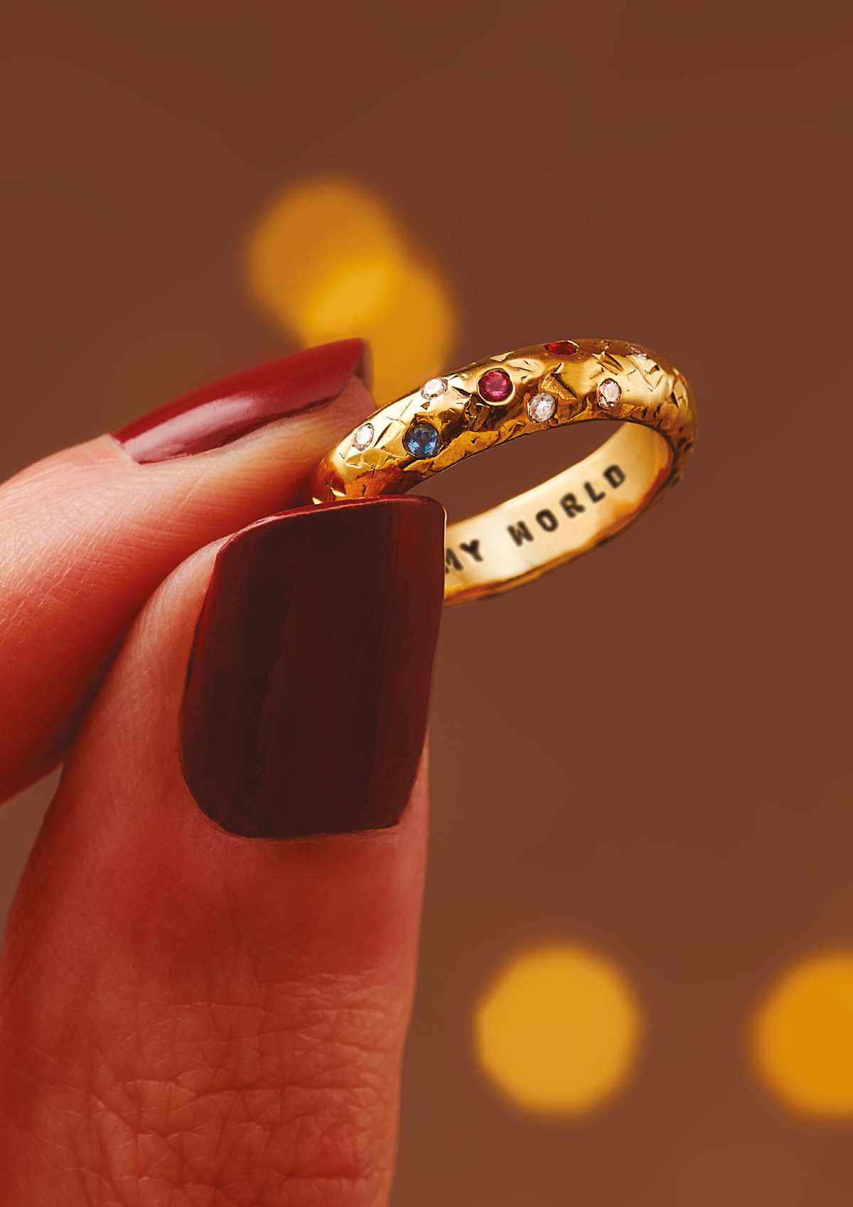 Gold confetti birthstone ring held against warm lights