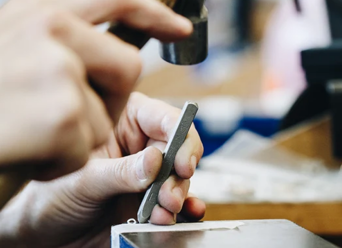 A jeweller holding a ring while working at the bench